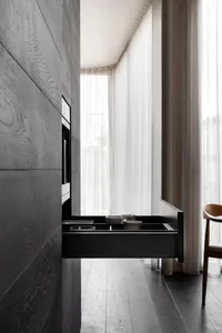 Modern black kitchen cabinets with wooden elements and white counter.