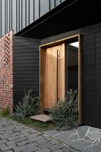 A modern front door with a wooden frame and a stone step in front of it.
