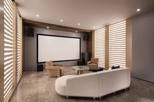 A modern home theater interior with a white screen, beige armchairs, and a white sofa.