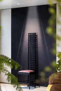 A black ladder-style chair with a pink cushion in a modern interior setting.