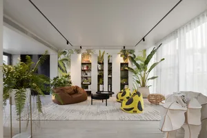 A modern interior design living room with a plant-based theme, featuring comfortable seating, bookshelves, and lush greenery.