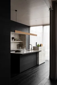 Modern kitchen with marble countertops and black wooden floors.