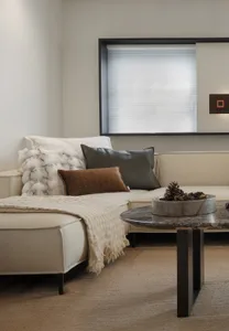 A modern living room featuring a white leather sofa adorned with colorful pillows and a cozy fur blanket, alongside a coffee 
