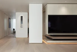 Modern living room featuring light-colored wooden floors, glass walls, and minimalist furniture.