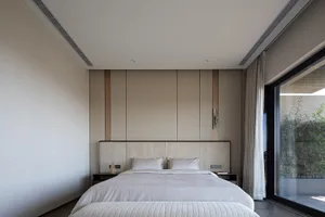 Modern minimalist bedroom featuring neutral-toned furniture and decor, clean lines, and a large window.
