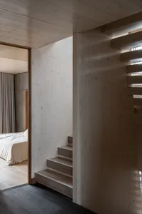 A modern minimalist staircase built from wooden steps and walls.