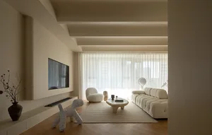 A modern living room with neutral-toned furniture, large windows, and minimal decor.