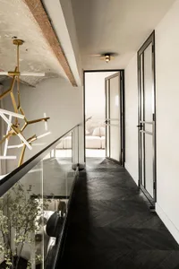 Modern residential corridor featuring dark wood flooring, white walls, and a sleek, contemporary design.