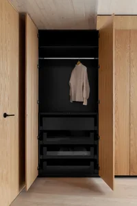 A modern wardrobe with wooden doors and black interior, showcasing a minimalist design.