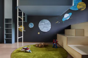 A children's playroom featuring a space-themed mural with various planets on the walls, a green rug, and toy spaceships on th