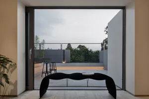 Modern interior space with sleek black bench, glass walls, and concrete flooring.