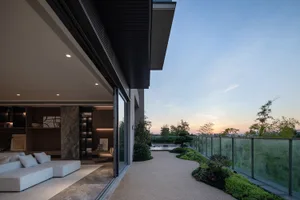 Modern residential patio featuring concrete walkway and glass railings.