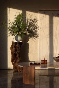 Marble coffee table and wooden stool in a living room with natural light streaming in through the windows.