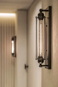 Industrial metal sconces with a long filament bulb mounted on a wall.
