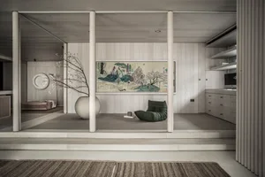 Minimalist living room featuring a wooden floor and furniture, with a large tapestry and a green beanbag chair.