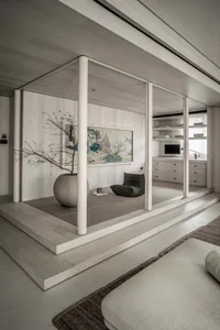 A modern minimalist living room with a Zen pod featuring a potted tree and a framed painting.