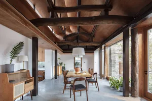 A modern dining room with wood beams, concrete floor, and wooden furniture.