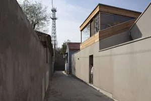 A modern exterior building made of concrete materials with large windows and a metal antenna tower in the background.