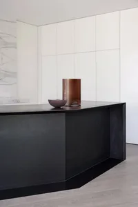 A modern kitchen with sleek, dark concrete countertops and minimalist white cabinets.