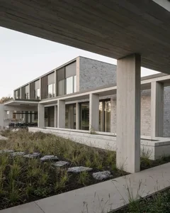 Modern residential house with concrete exterior and large windows.