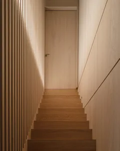 Modern wooden staircase with light wall and door.