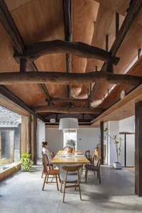 A modern, industrial dining room with exposed wooden beams on the ceiling.