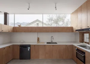 Minimalist apartment interior with wooden furniture and white countertops.