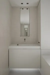 Modern minimalist bathroom with concrete walls and a stainless steel sink.