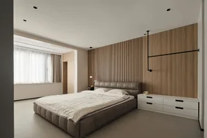 A minimalist bedroom with a wooden accent wall and a bed with a padded headboard.