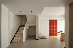 Modern minimalist living room featuring concrete flooring, white walls, and orange shelving.