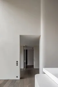 A minimalist interior space featuring concrete elements and a tall ceiling.