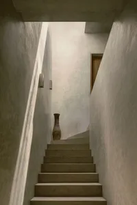 A minimalist interior with concrete stairs and a vase at the bottom.