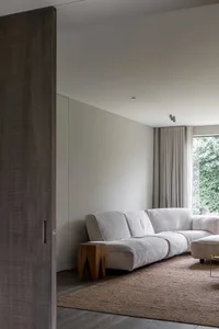Modern minimalist living room with soft fabric sofa and wooden stools.