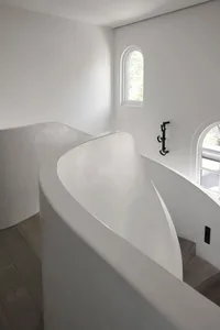 Modern, minimalist staircase with curved concrete treads and white walls.
