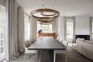 Modern dining room featuring natural wood dining table and chairs, with large windows, pendant lighting, and clean lines.