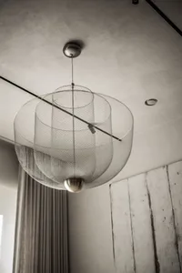 A modern interior with a metal mesh and brass lamp hanging from the ceiling.