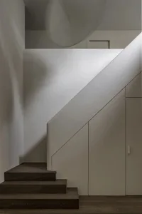 Modern interior design featuring wooden stairs with a white railing.