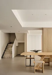 A well-lit, modern interior space featuring a wooden table, chairs, and minimalist design elements.