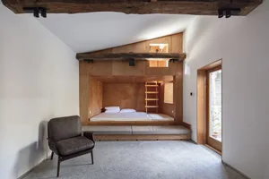 A modern minimalist bedroom with wood features and a bed built into the wall.