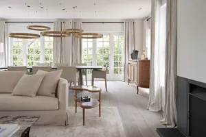 Modern living room with neutral tones, featuring a comfortable sofa, a sleek coffee table, and a dining table with chairs.