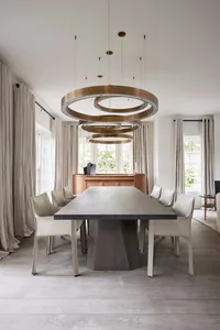 A modern residential dining room with a concrete table and chairs, surrounded by large windows and a minimalist interior desi