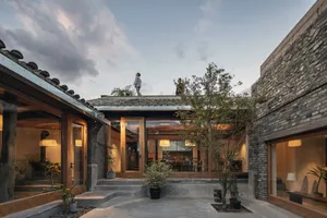 A cozy courtyard with wooden doors, concrete steps, and stone walls and roofs in a residential Chinese-style home.