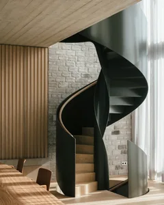 A modern, black metal spiral staircase with wooden steps and railings.