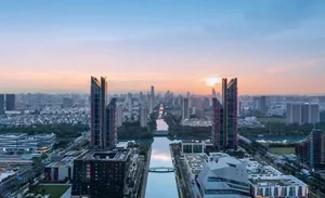 Modern urban landscape featuring glass, concrete, and steel buildings at sunset.