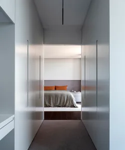 A modern, minimalist bedroom with white walls, flooring, and furniture.