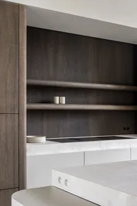 A modern minimalist kitchen with concrete and wood finishes and white shelves.