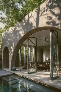 A minimalist patio featuring concrete walls and a small pool, surrounded by lush greenery.