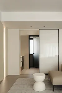 Modern minimalist kitchen with white cabinets, a white speckled table, and a beige couch.