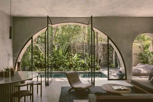 Modern residential interior featuring concrete walls and glass doors with a view of a pool and garden.