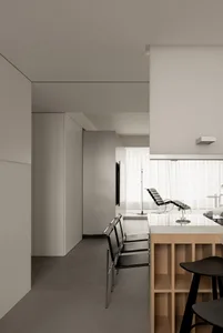 Minimalist residential kitchen featuring modern design with wooden island and metal chairs.